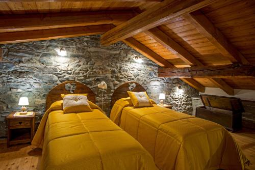 two beds in a room with a stone wall at La cor dé Jérémie in Montjovet