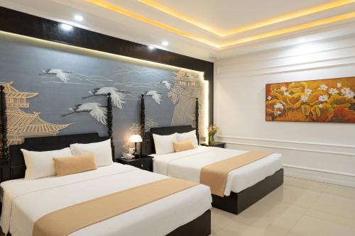 a bedroom with two beds and a painting on the wall at The Elegant Boutique - Hue in Hue
