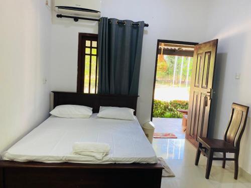a bedroom with a bed and a chair and a window at Forest Edge Yala Resort in Gotamegama