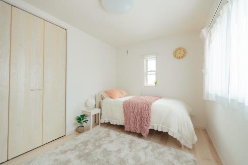 a white bedroom with a bed and a clock on the wall at Quiet Japanese House near Airport in Kumamoto