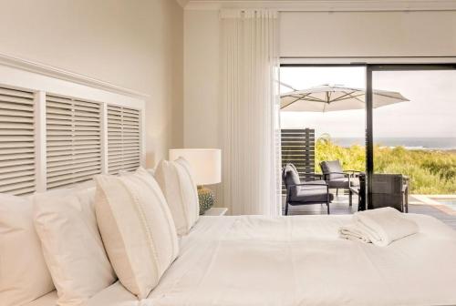 a bedroom with a white bed with a view of the ocean at Baudin Beach House in Gnarabup