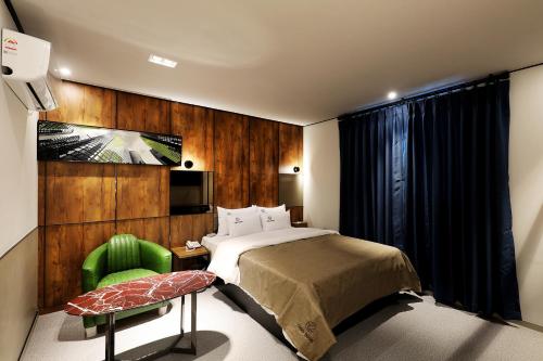 ein Schlafzimmer mit einem Bett und einem grünen Stuhl in der Unterkunft Cielo HOTEL in Seosan