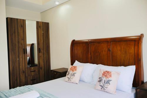 a bedroom with a bed with a wooden headboard and pillows at Studio Getaway in Cebu City Baseline in Cebu City