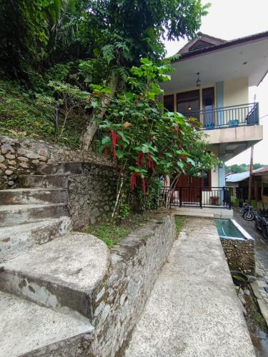 a building with a stone staircase next to a house at Monkey Business Tours & Accommodation in Bukit Lawang