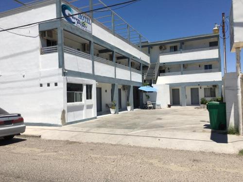 ein weißes Gebäude mit einem Parkplatz davor in der Unterkunft Pearl Point Hotel in Puerto Peñasco