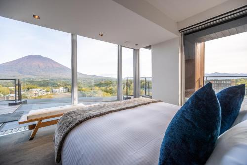 a bedroom with a large bed and large windows at The Vale Niseko in Kutchan