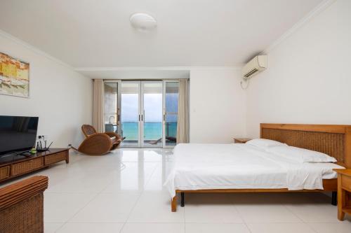 a white bedroom with a bed and a television at Yumian Cloud Seaview Hotel in Sanya