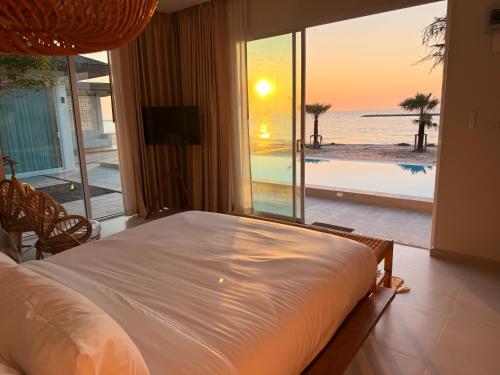 a bedroom with a bed and a view of the ocean at Wind Haus Beachfront Villa in Ban Hat Chao Samran