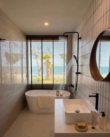 a bathroom with a tub and a sink and a window at Wind Haus Beachfront Villa in Ban Hat Chao Samran