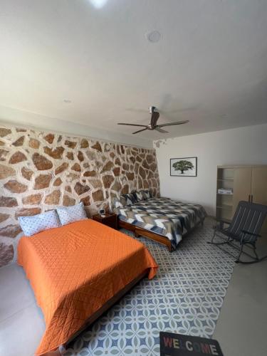 a bedroom with two beds and a stone wall at Viveza - Downtown in Campeche