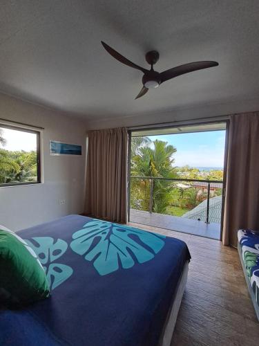 a bedroom with a blue bed and a large window at ARIIMOE Hava'e in Teahupoo