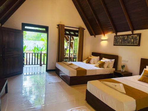 a bedroom with two beds and a balcony at Oak Haven Cabana Sigiriya in Sigiriya