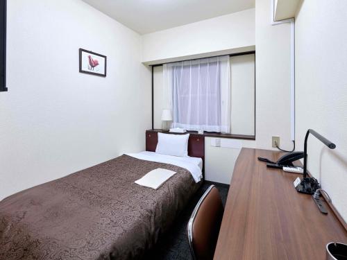 a hotel room with a bed and a desk at Dai-ni Sunny Stone Hotel in Osaka