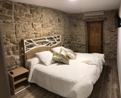 a bedroom with a white bed with a stone wall at La Casona de Alútiz & Bodega in Samaniego