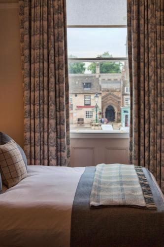 a bedroom with a bed and a large window at The Falcon Hotel in Uppingham