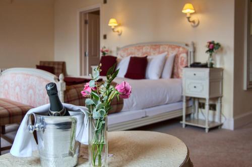 a living room with a bed and a table with a bottle of wine at The Falcon Hotel in Uppingham