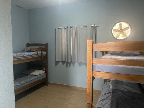 a room with bunk beds and a clock on the wall at Apê Bianck's in Ilha Comprida