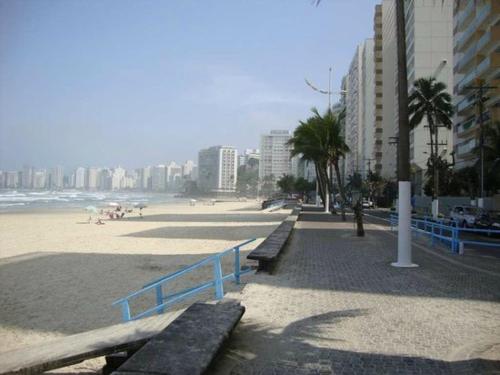 a beach with benches and buildings and the ocean at Apartamento Pitangueiras - Guaruja in Guarujá