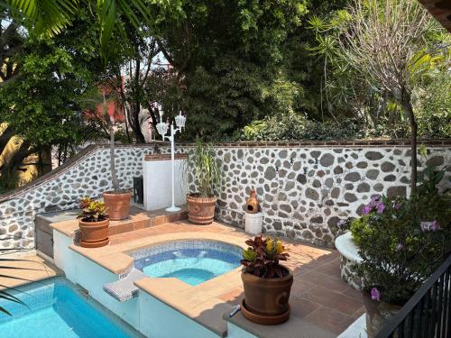 a swimming pool with potted plants in a backyard at Linda Villa al lado del Club de Tenis in Cuernavaca