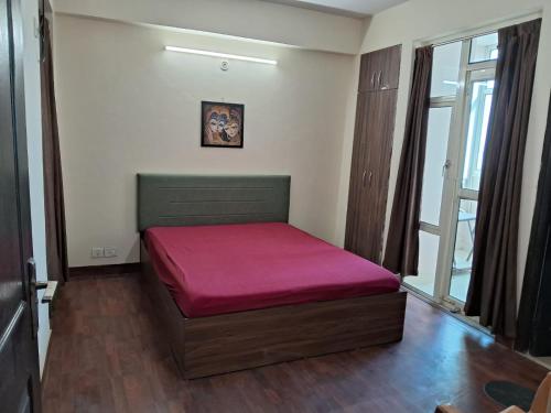 a bed in a room with a red mattress at Friendly Service Apartment in Ghaziabad