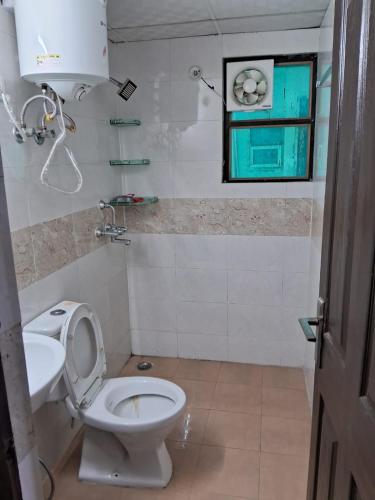 a bathroom with a toilet and a sink and a window at Friendly Service Apartment in Ghaziabad
