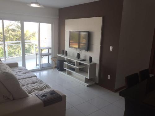 uma sala de estar com um sofá e uma televisão em Apto Bella Aurora em Cabo Frio