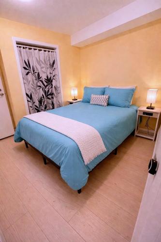 a bedroom with a blue bed with two tables and a window at CasaViva Garden - 2BR with Firepit, S'mores & Kids Playset - Walk to Eats, Near Zoo, SeaWorld & Balboa Park in San Diego