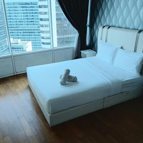 a white bed with a teddy bear sitting on it at Vortex suites klcc by kl cozy home in Kuala Lumpur