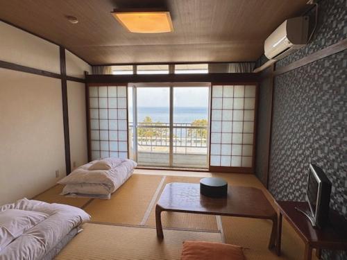 a room with two beds and a table and a window at Eboshiso in Tamagawa