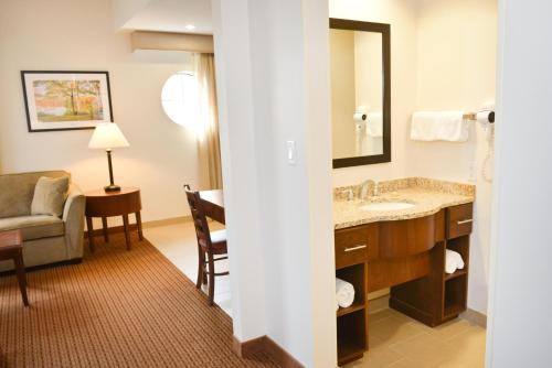 a hotel room with a bathroom with a sink and a chair at Penn Wells Lodge in Wellsboro