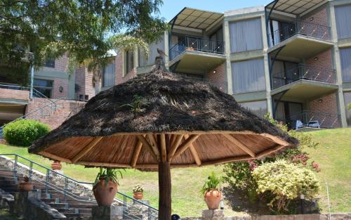 a large straw umbrella in front of a building at Hotel Del Dique in Coronel Moldes