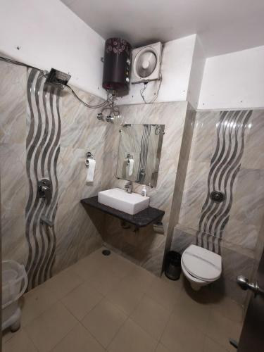 a bathroom with a sink and a toilet and a tv at Hotel The Siwan International in Siwān