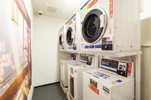 a laundry room with three washing machines on display at KOKO HOTEL Residence Kyoto Nijo Castle in Kyoto