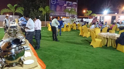 a group of people standing in a field with tables and chairs at Rosewood International Hotel in Bengaluru