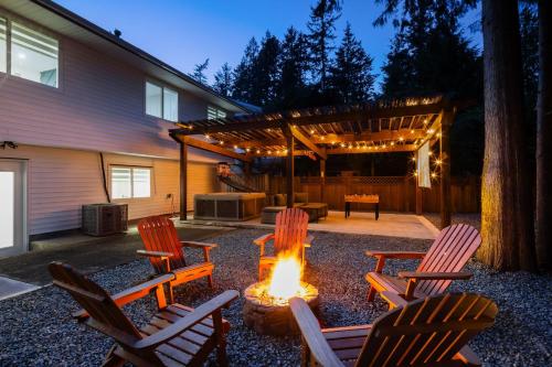 a backyard with chairs and a fire pit and a pergola at Bunny Bliss - Upper Level HotTub FirePit Theatre in Langley