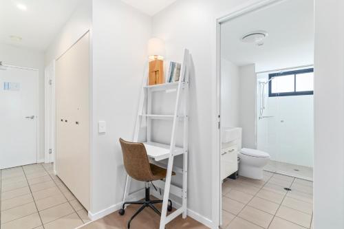 a white bathroom with a desk and a chair at Direct Collective - Sea Breeze Mooloolaba in Mooloolaba
