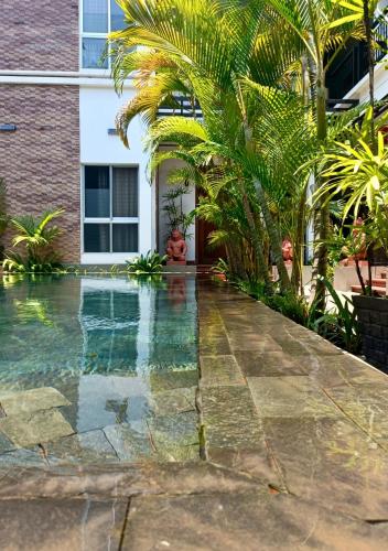 a swimming pool in front of a house with palm trees at La Fontaine de Tara Boutique Hotel in Siem Reap