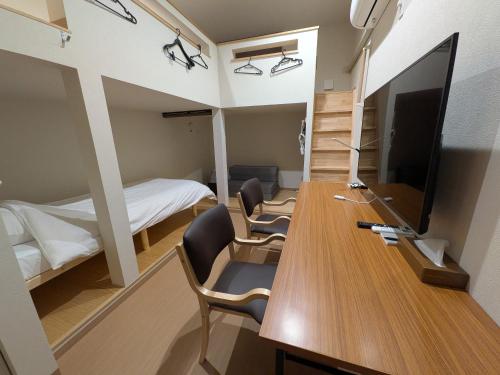 a room with a desk with chairs and a television at Hiroshima Saijo Youth Hostel in Higashihiroshima