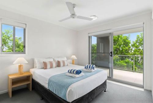 a white bedroom with a bed and a large window at Direct Collective - Breeze on Brightwater in Mooloolaba