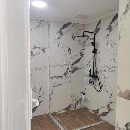 a bathroom with a marble wall with a shower at Zenith Apartment in Bitola