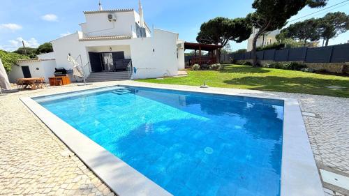 a large blue swimming pool in front of a house at Casa Da Laranjeira- Serene 4Bedroom 4Bath Pool & Garden Villa, 10 mins to Vilamoura Marina in Quarteira