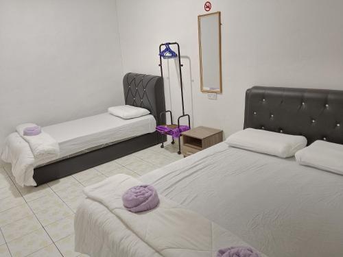 a bedroom with two beds with purple towels on them at Rumah Impian Bapa in Semporna