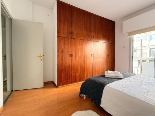 a bedroom with a bed and a wooden cabinet at Mimosa flat City Cente 2bdr in Nicosia