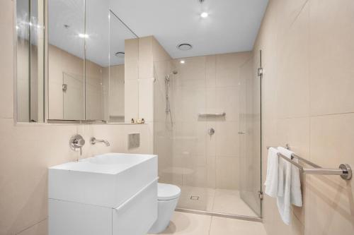 a white bathroom with a toilet and a shower at Rooftop infinity pool - St Kilda luxury in Melbourne