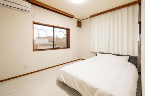 a bedroom with a white bed and a window at Dream Bridge Fuji House in Fuji