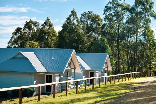 two houses with a blue roof and a fence at Brokenback Views Country Estate Hunter Valley in Pokolbin