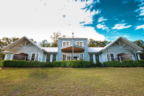 a blue house with a large yard in front of it at Brokenback Views Country Estate Hunter Valley in Pokolbin
