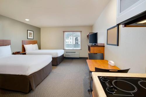 a hotel room with two beds and a kitchen at WoodSpring Suites Columbus NE I-270 Airport in Gahanna