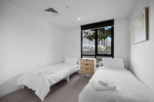 two beds in a room with a window at Rooftop infinity pool - St Kilda luxury in Melbourne