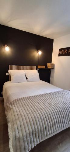 a bedroom with a large white bed with a black wall at Le Désiré in Arras